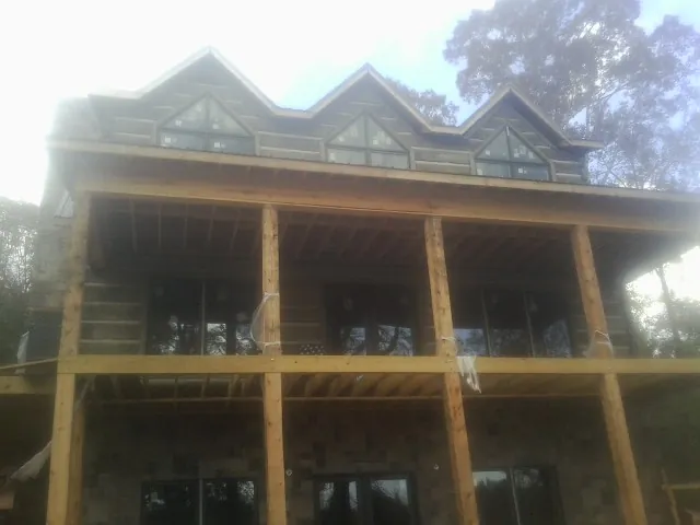 Dormers and porch framing on a large log home under construction — Roof Coating work by our crew in Tarzan