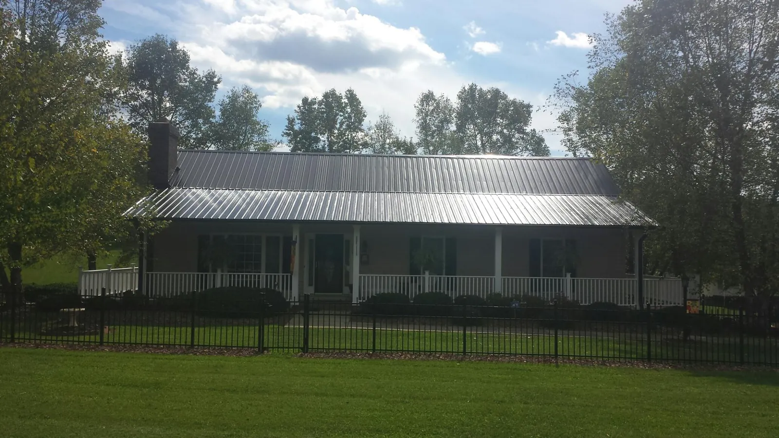 Gray metal roof on a brick ranch with a full width front porch — Gutter Guard Installation work by our crew in Tarzan