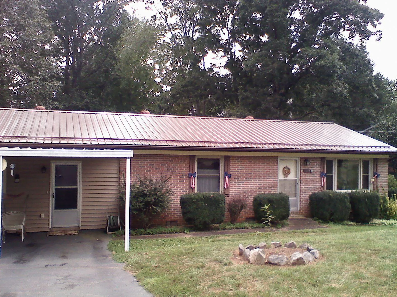 Bronze metal roof and carport on a brick ranch home — Roof Repair work by our crew in Tarzan