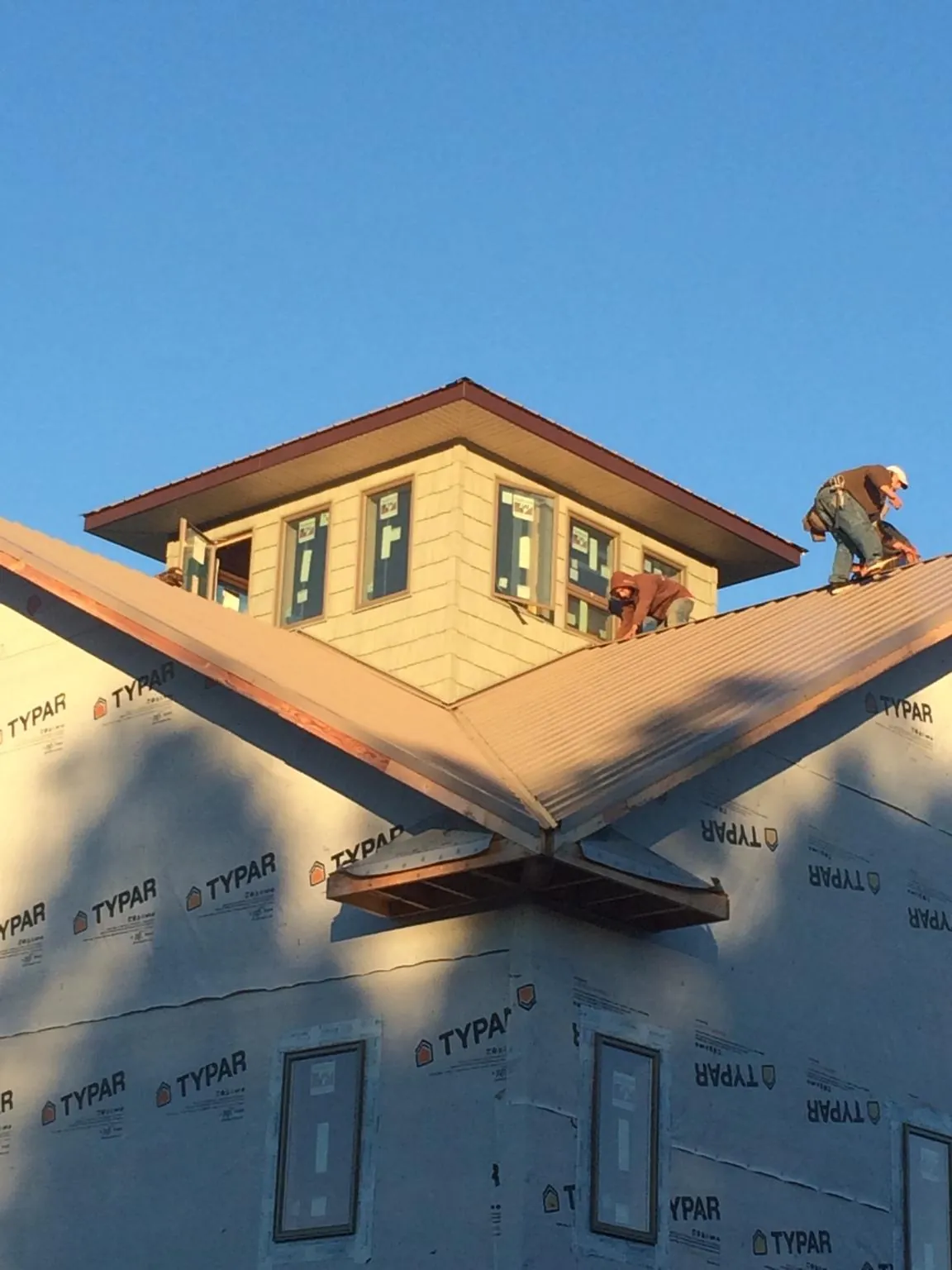 Roofers working around a rooftop cupola on a new metal roof at sunset — Roof Waterproofing in Tarzan by Roofing Brothers